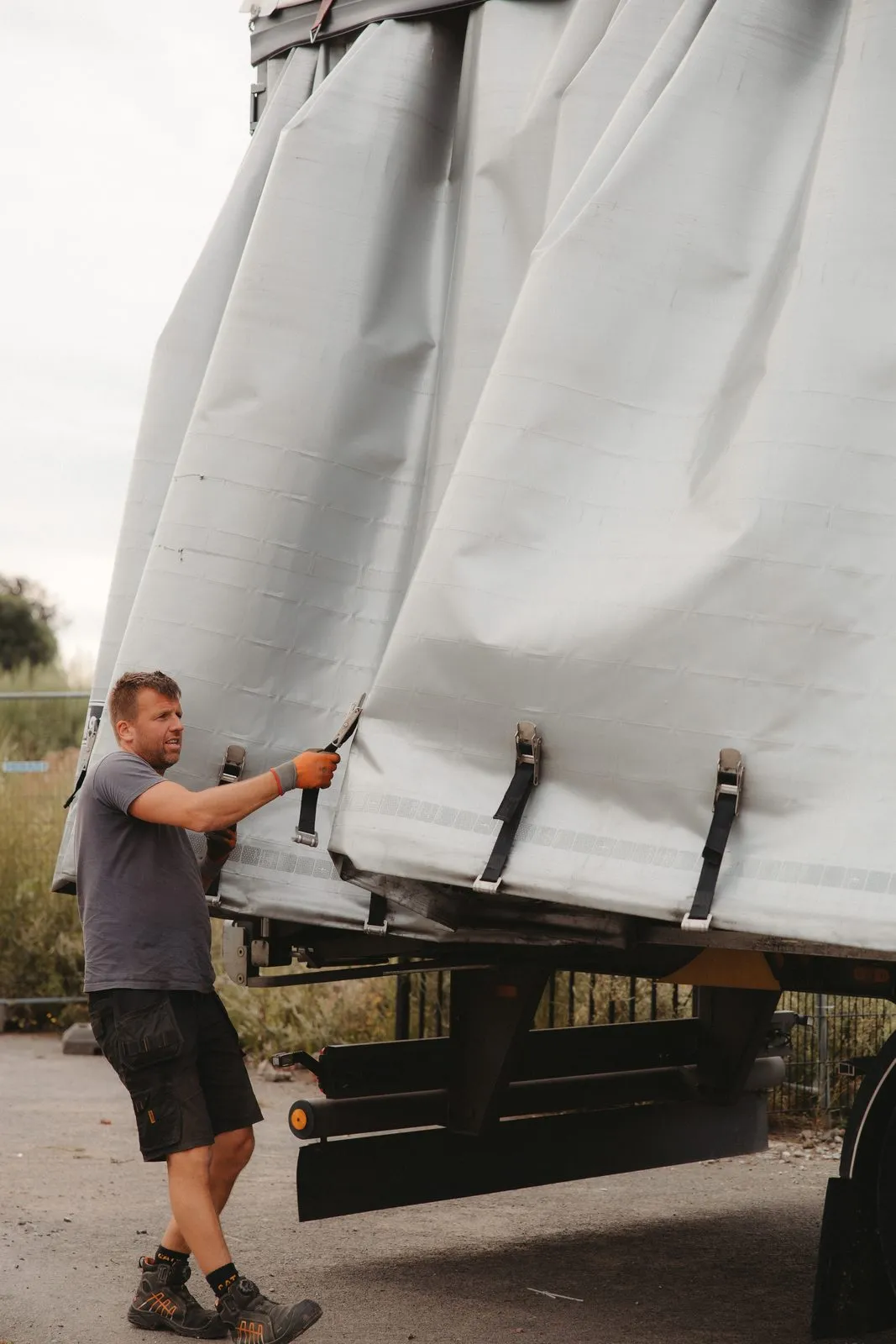 Bram opent de zeilen van een oplegger vol blauwe staanders