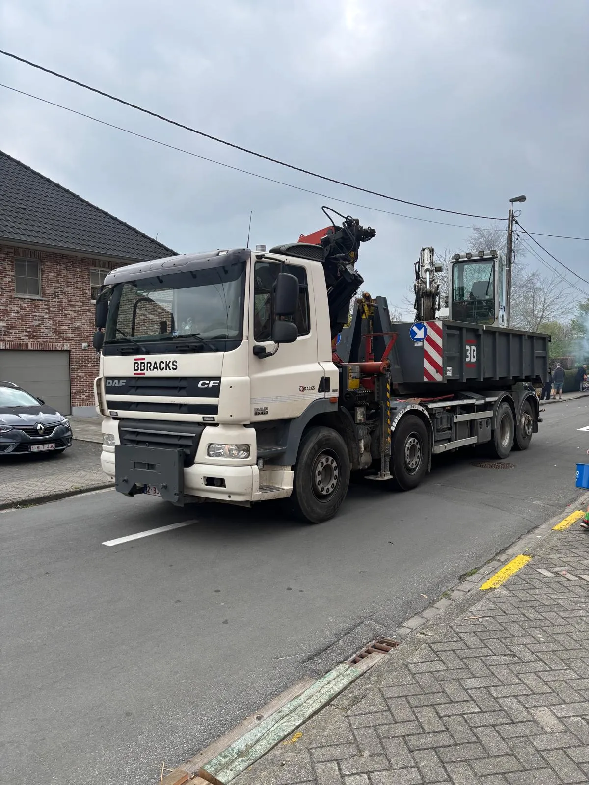 Witte DAF-vrachtwagen van BB Racks met kraan laadt een afvalcontainer