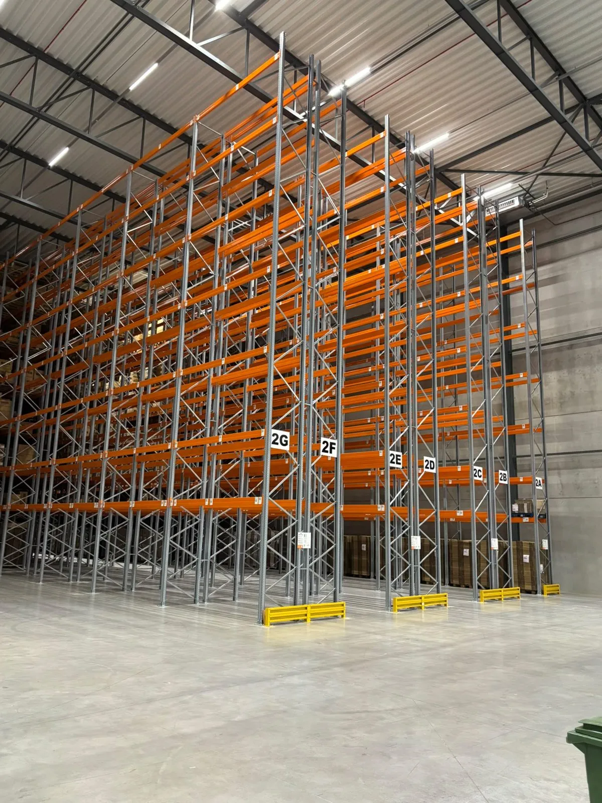Hoge palletstellingen met grijze staanders en oranje liggers in een nieuwe, lege hal