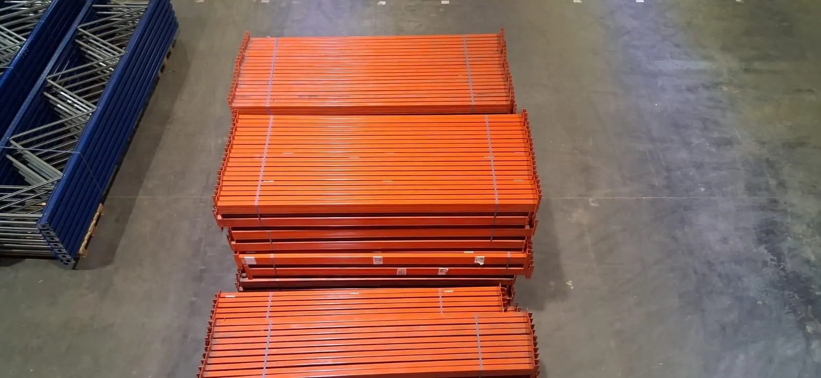 Twee stapels oranje liggers naast een rij blauwe staanders